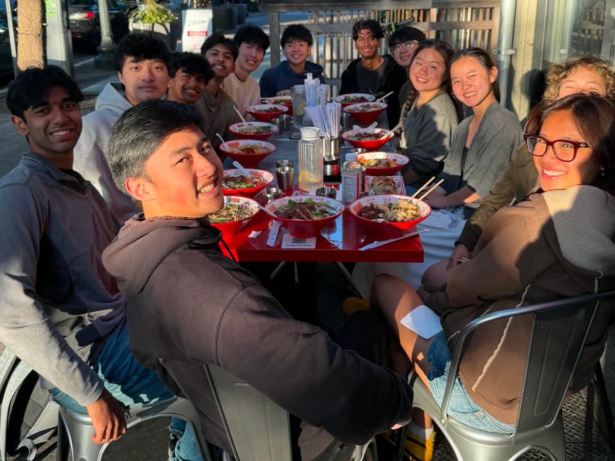 Acadev committee members gathered around a long outdoor table of noodle bowls at a Berkeley restaurant, turning to smile at the camera