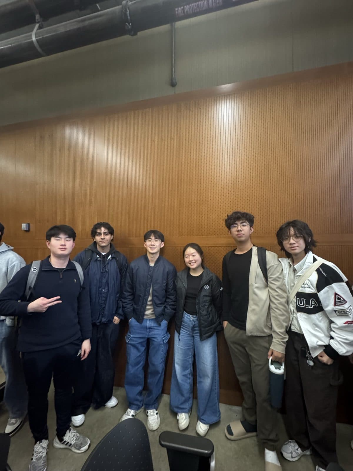 A DeCal project group standing together at the front of their classroom after class.