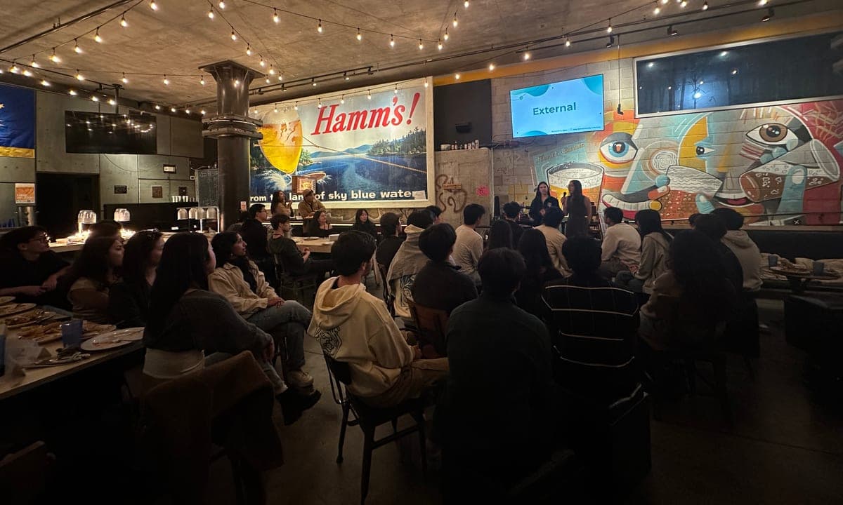 DSS members seated around tables listening to speakers at an evening alumni and industry event