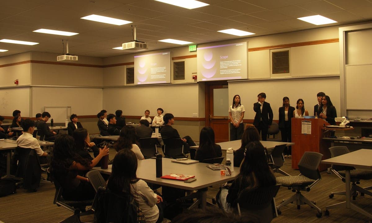 A DSS project team in business attire presenting their work to seated members in a classroom
